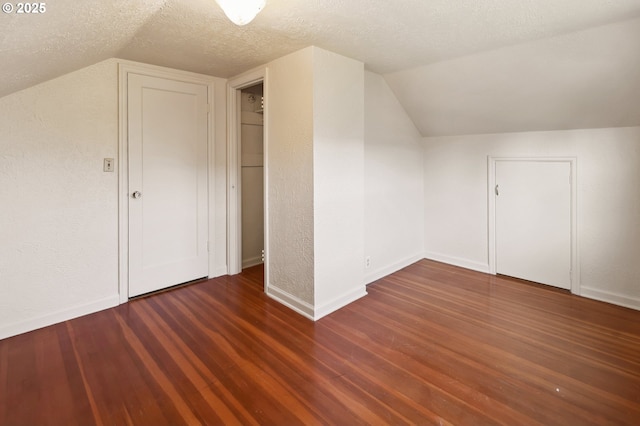 additional living space featuring lofted ceiling, baseboards, a textured ceiling, and wood finished floors
