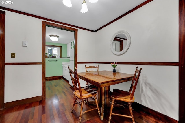 dining room with crown molding, baseboards, and wood finished floors