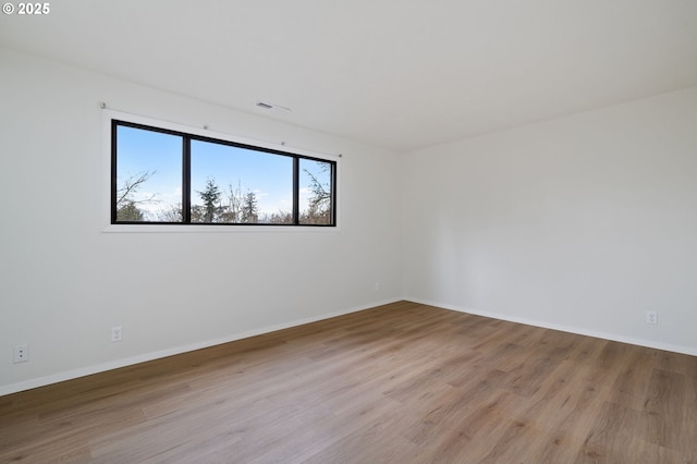 empty room with visible vents, baseboards, and wood finished floors