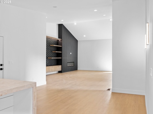 interior space featuring lofted ceiling, baseboards, and light wood finished floors