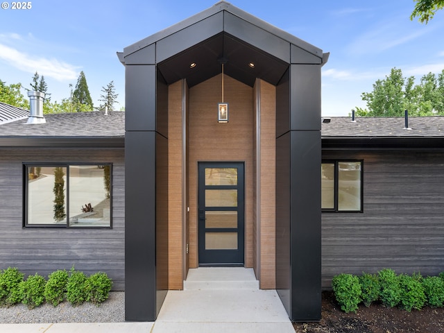doorway to property with roof with shingles