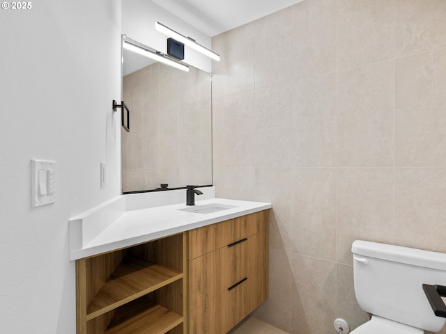 bathroom with tile walls, toilet, and vanity