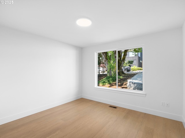 unfurnished room with baseboards, visible vents, and wood finished floors