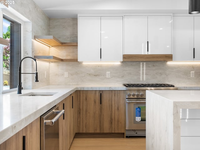 kitchen with light stone counters, modern cabinets, a sink, open shelves, and stainless steel appliances