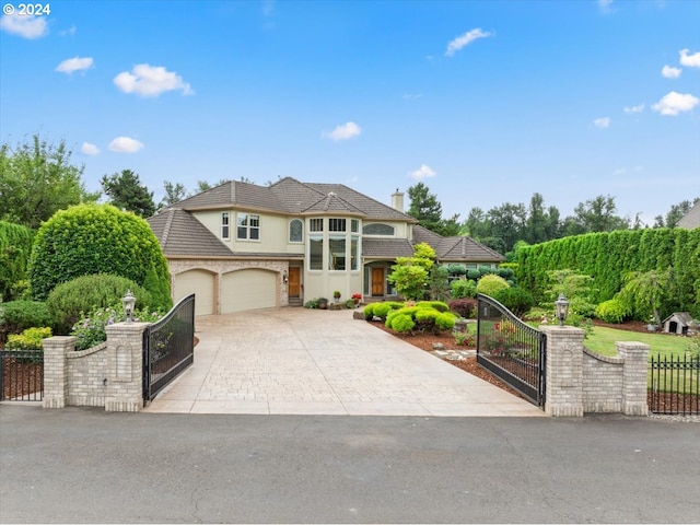french country inspired facade featuring fence, stucco siding, driveway, a garage, and a gate