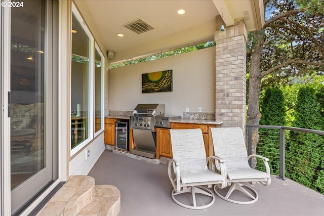view of patio with beverage cooler, exterior kitchen, grilling area, and a balcony