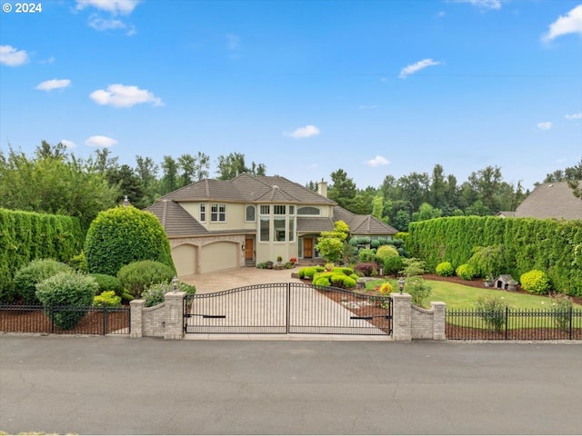 view of front facade featuring a gate, stucco siding, driveway, and an attached garage