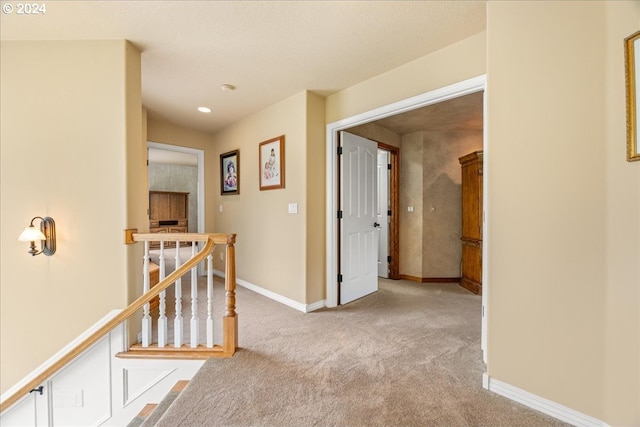 corridor featuring carpet flooring, baseboards, recessed lighting, and an upstairs landing