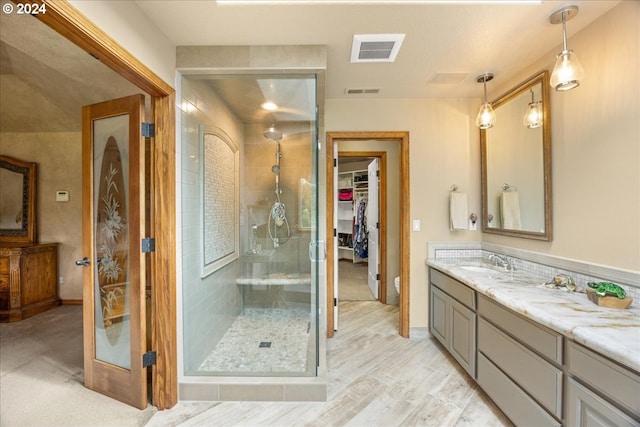 bathroom with a stall shower, vanity, a spacious closet, and wood finished floors