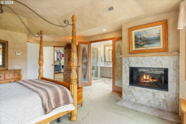 bedroom with light carpet, a fireplace, ensuite bath, a spacious closet, and recessed lighting