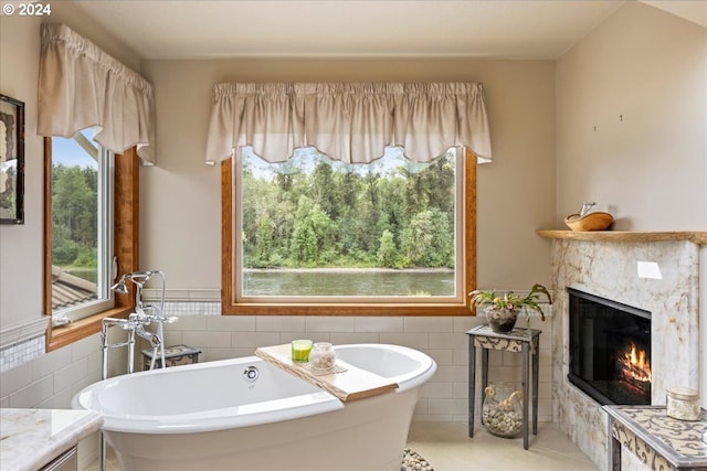 full bath with tile walls, a high end fireplace, a freestanding tub, tile patterned flooring, and wainscoting