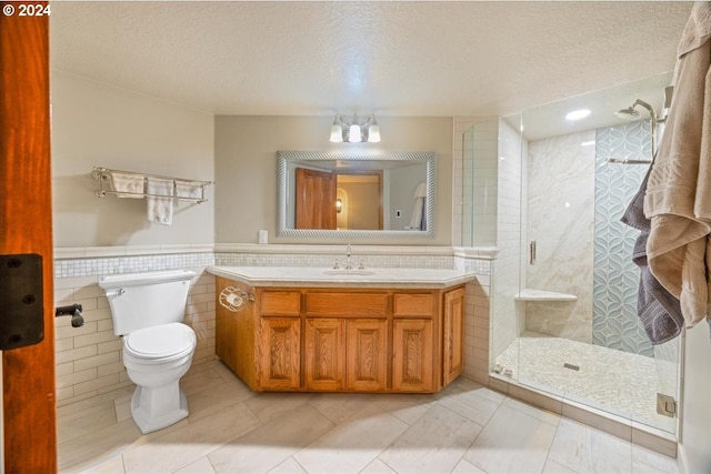 full bath with tile walls, a textured ceiling, a shower stall, toilet, and vanity