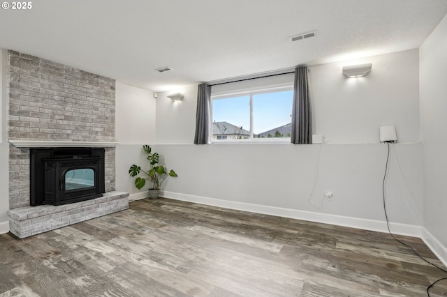 unfurnished living room with a brick fireplace, hardwood / wood-style floors, and a textured ceiling