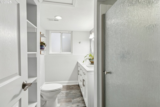 bathroom featuring hardwood / wood-style flooring, vanity, walk in shower, and toilet