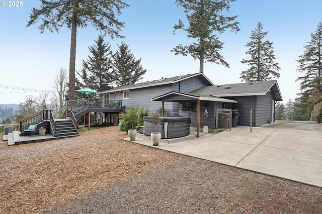 rear view of property with a hot tub, a deck, and a patio