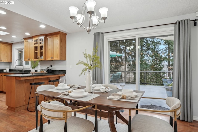 dining area featuring sink, a notable chandelier, light hardwood / wood-style floors, and a textured ceiling