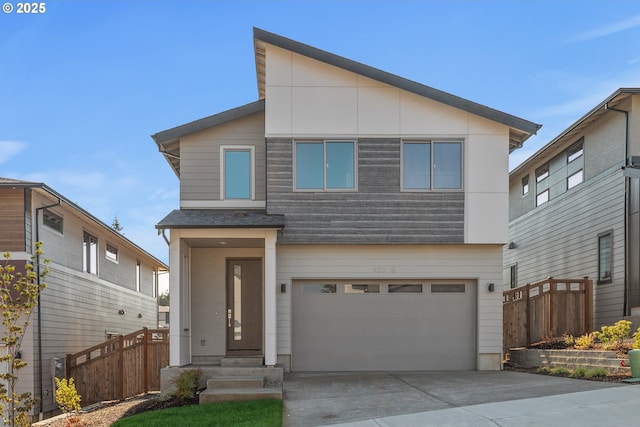 modern home featuring an attached garage, fence, and concrete driveway