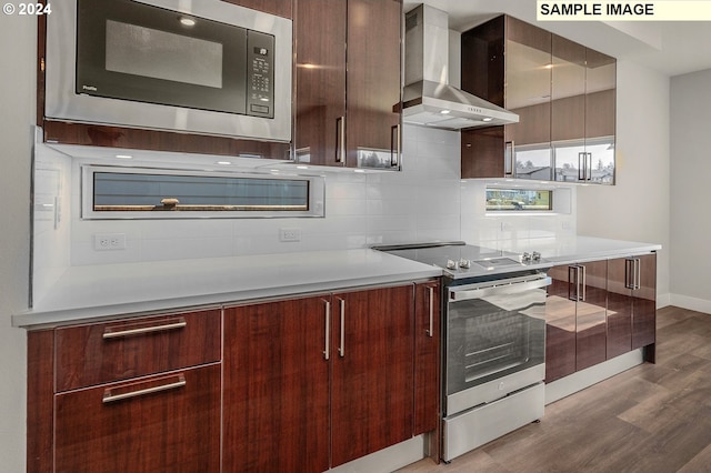 kitchen featuring stainless steel electric stove, light countertops, wall chimney range hood, modern cabinets, and built in microwave