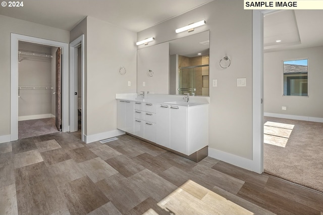 bathroom with baseboards, double vanity, a sink, and a shower stall