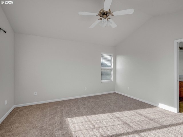 spare room featuring vaulted ceiling, carpet, and baseboards