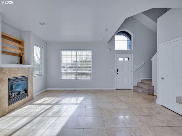 foyer entrance featuring a tile fireplace, plenty of natural light, stairway, and light tile patterned floors