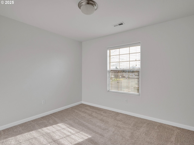 unfurnished room with visible vents, light carpet, and baseboards