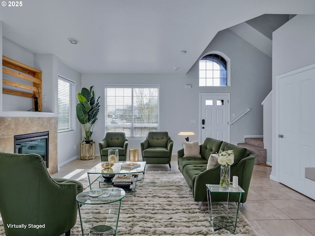 living room with light tile patterned floors, lofted ceiling, a tile fireplace, baseboards, and stairs