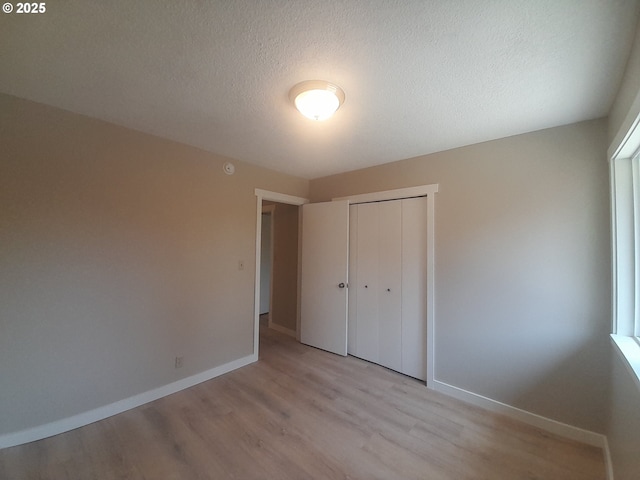 4810 SW 48th Ct, Lincoln City, OR 97367 - unfurnished bedroom featuring light wood-type flooring, a closet, baseboards, and a textured ceiling