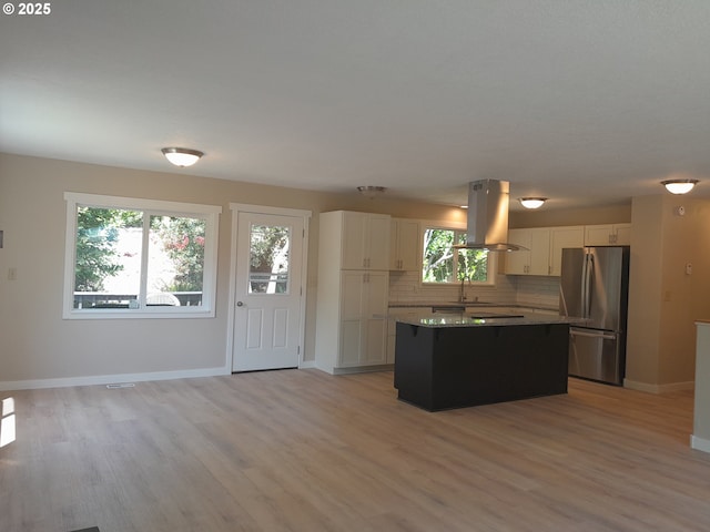 4810 SW 48th Ct, Lincoln City, OR 97367 - kitchen featuring freestanding refrigerator, island range hood, a kitchen island, backsplash, and white cabinetry