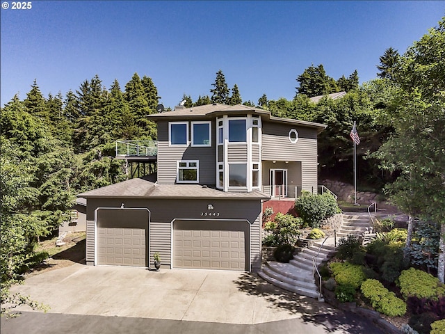 view of front of property featuring stairway, a balcony, concrete driveway, and an attached garage