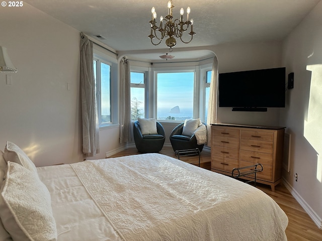 bedroom with a chandelier, visible vents, baseboards, and wood finished floors