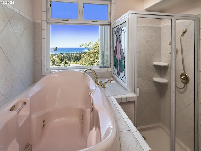 bathroom with a shower stall, a jetted tub, and a water view