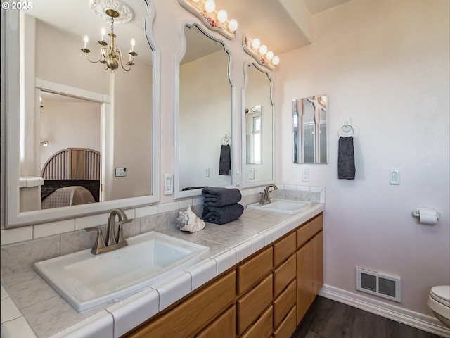 ensuite bathroom with double vanity, visible vents, connected bathroom, and a sink