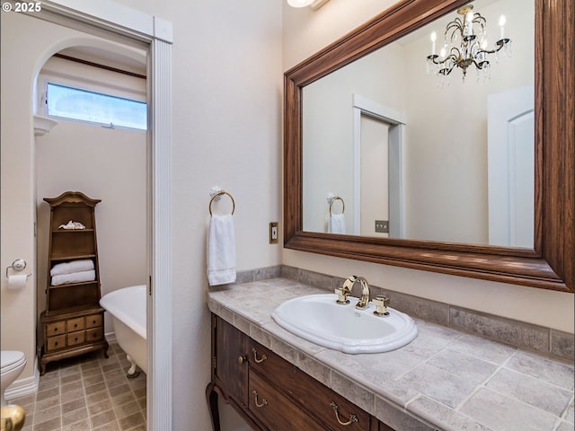 bathroom featuring toilet, a freestanding bath, and vanity