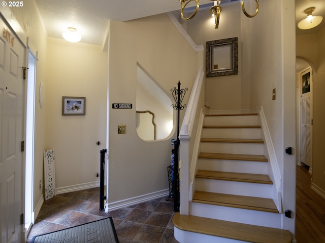 stairs featuring arched walkways, baseboards, and stone finish flooring