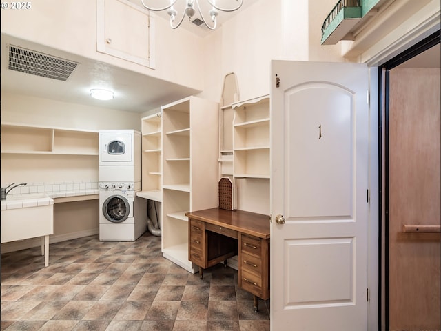 laundry area featuring visible vents, stacked washer and clothes dryer, laundry area, and stone finish flooring