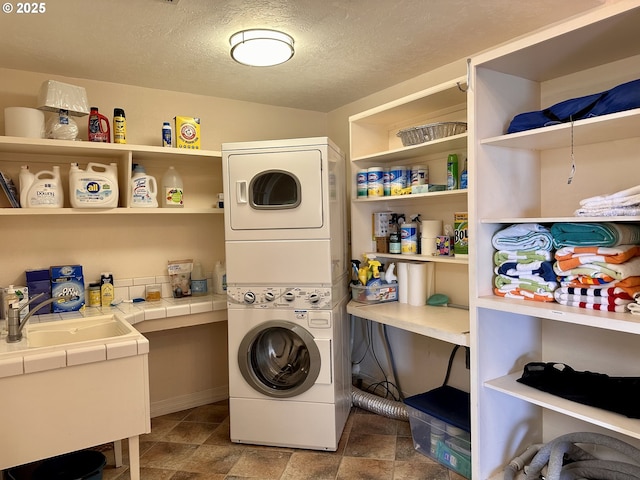 35445 Topping Rd, Pacific City, OR 97135 - washroom with a textured ceiling, stacked washer and dryer, a sink, and laundry area