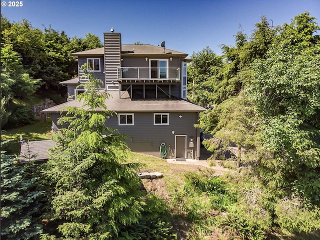 rear view of property with a chimney and a balcony