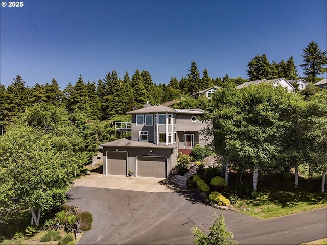 view of front facade with a garage, a balcony, and driveway