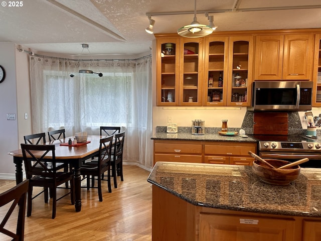 35445 Topping Rd, Pacific City, OR 97135 - kitchen featuring brown cabinetry, glass insert cabinets, stainless steel appliances, and light wood-style floors