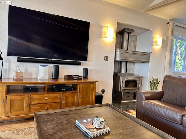 living room with a wood stove, light wood-style floors, and a textured wall