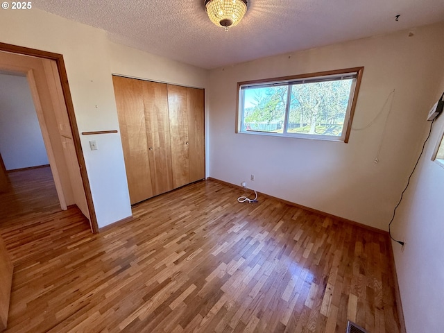 unfurnished bedroom with light hardwood / wood-style floors, a textured ceiling, and a closet