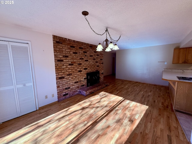 unfurnished living room featuring a fireplace, an inviting chandelier, wood-type flooring, and a textured ceiling