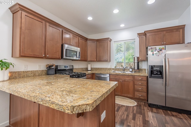 5065 SW 207th Pl, Beaverton, OR 97078 - kitchen featuring appliances with stainless steel finishes, a sink, a peninsula, dark wood-style floors, and brown cabinets