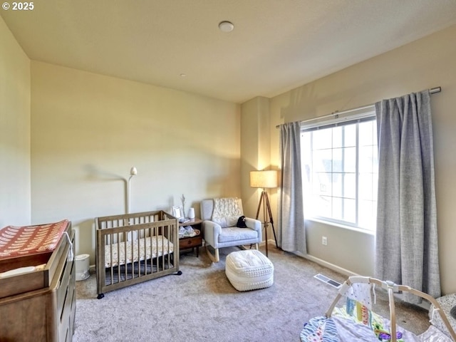 bedroom with a crib, visible vents, and carpet floors