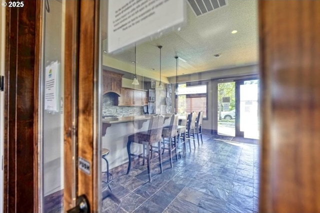 dining room with a textured ceiling, visible vents, stone finish flooring, and recessed lighting