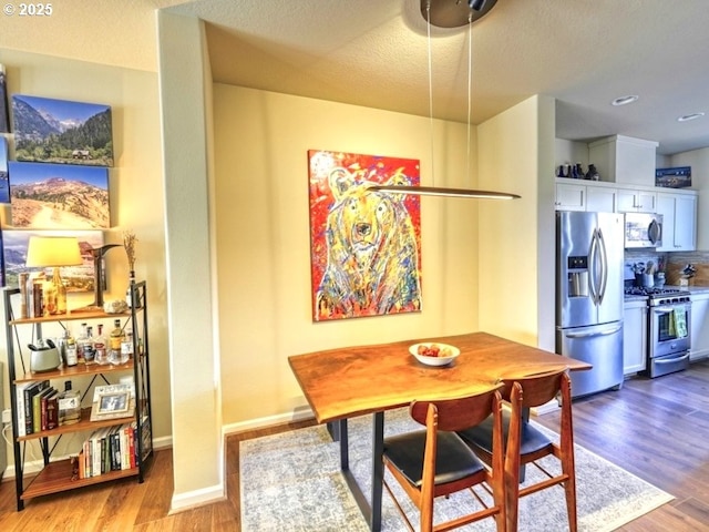 dining room with baseboards, a textured ceiling, and wood finished floors