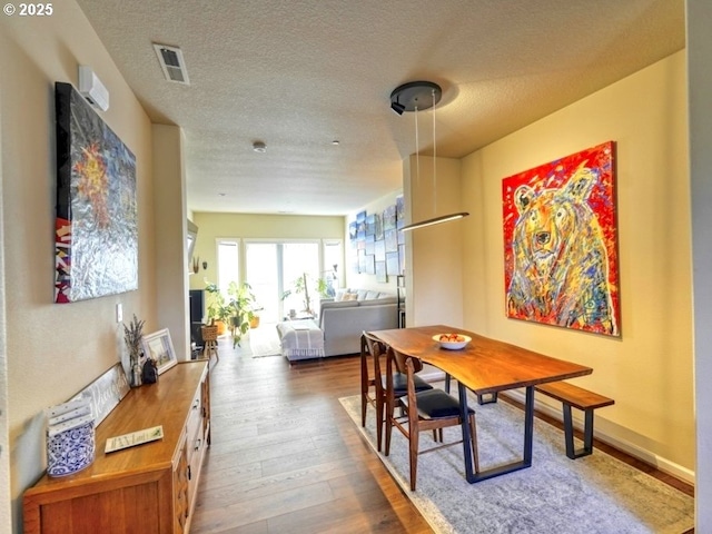 dining room with a textured ceiling, wood-type flooring, and visible vents