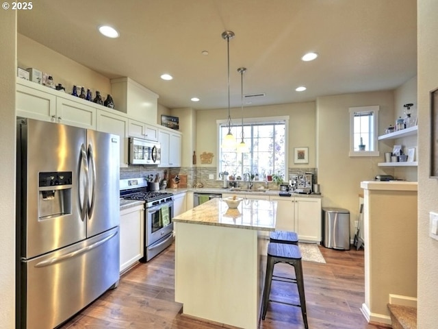 kitchen featuring a center island, decorative light fixtures, appliances with stainless steel finishes, decorative backsplash, and recessed lighting