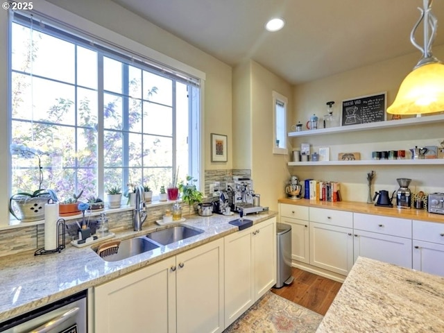 kitchen with white cabinets, wood finished floors, a healthy amount of sunlight, and a sink